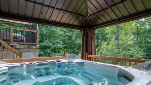 A hot tub under a wooden deck with a view of a forest. - Spa & Nature | Le Havre du Confort (Saint-Colomban)