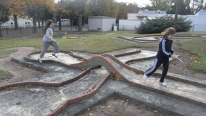 Due bambini giocano su una struttura in cemento con gradini e bordi in mattoni in un parco.