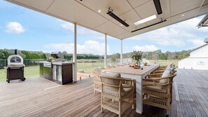 An outdoor patio with a grill, wicker furniture, and a view of the countryside. - Silos – rural homestead on 50 acres (East Kangaloon)