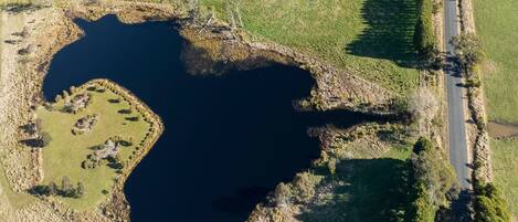 An aerial view of a lake with a small island and a road running parallel to the water's edge.