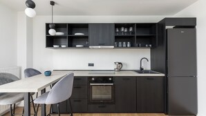 Uma cozinha moderna com armários escuros, forno embutido e geladeira.