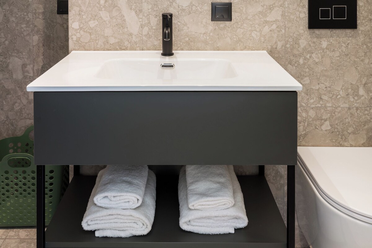 Une salle de bain avec un lavabo blanc, un miroir rond et des toilettes.
