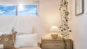 A bedroom with a bed, bedside table with a lamp, a wooden nightstand, and a window with a view of the sky. - Casablanca by Khove (Labrador)