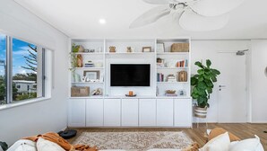 A modern living room with a large TV, white cabinetry, and a ceiling fan. - Casablanca by Khove (Labrador)