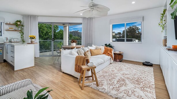 A spacious living area with a white sofa, a wooden coffee table, and a large window offering a view of greenery and buildings. - Casablanca by Khove (Labrador)