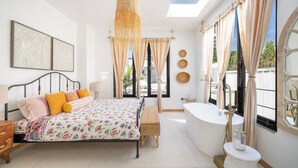 A bedroom with a bed, bedside table, and a large window with curtains. - Lux 6-bed villa with WiFi, generator and AC in enchanting San Juan, Puerto Rico (San Juan)