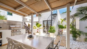 An outdoor dining area with a wooden table and chairs, surrounded by potted plants and a stone pathway. - Lux 6-bed villa with WiFi, generator and AC in enchanting San Juan, Puerto Rico (San Juan)