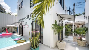 A modern outdoor pool area with a white building, potted plants, and a clear sky. - Lux 6-bed villa with WiFi, generator and AC in enchanting San Juan, Puerto Rico (San Juan)