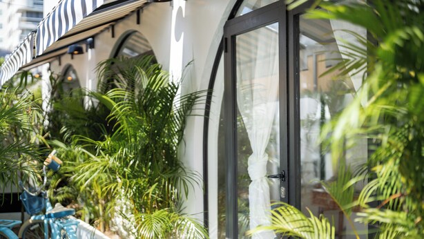 A hotel exterior with a large glass door, a bicycle parked outside, and lush green plants. - Lux 6-bed villa with WiFi, generator and AC in enchanting San Juan, Puerto Rico (San Juan)