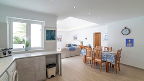 A modern kitchen with a built-in oven, a dining area with a table set for four, and a large window providing natural light.