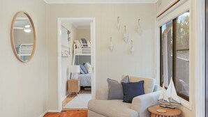 Een gezellige kamer met een stapelbed, een bank met kussens, een ronde tafel en een groot raam.