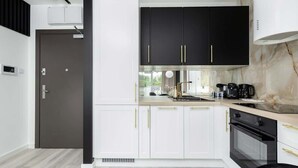 A modern kitchen with black and white cabinetry, a built-in oven, and a coffee maker.