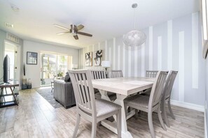 Ein Essbereich mit Holztisch und -stühlen, einem Deckenventilator und einer dekorativen Leuchte.