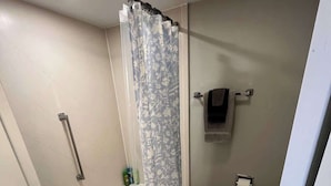 A bathroom with a bathtub, toilet, and shower curtain. - Modern Apartment Near Aksarben Village & Dining (Omaha)