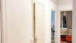 A hallway with a white door, a red couch, and a tiled floor.
