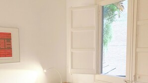 A bedroom with a bed, a nightstand, a window, and a wall-mounted picture.