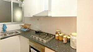 A compact kitchen with a gas stove, a sink, and cabinets.