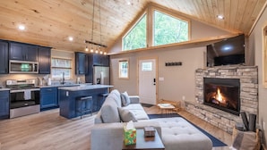 A modern kitchen with dark cabinets, a central island, and a built-in oven. - The Falcons Nest- Hot Tub - Fire Pit - Large Covered Porch (Bryson City)
