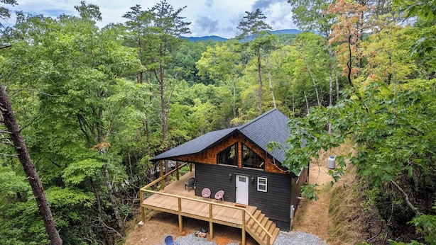 A cabin with a wooden deck, outdoor seating, and a gravel area. - The Falcons Nest- Hot Tub - Fire Pit - Large Covered Porch (Bryson City)