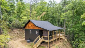 A cabin with a wooden deck and a staircase leading to a covered porch. - The Falcons Nest- Hot Tub - Fire Pit - Large Covered Porch (Bryson City)
