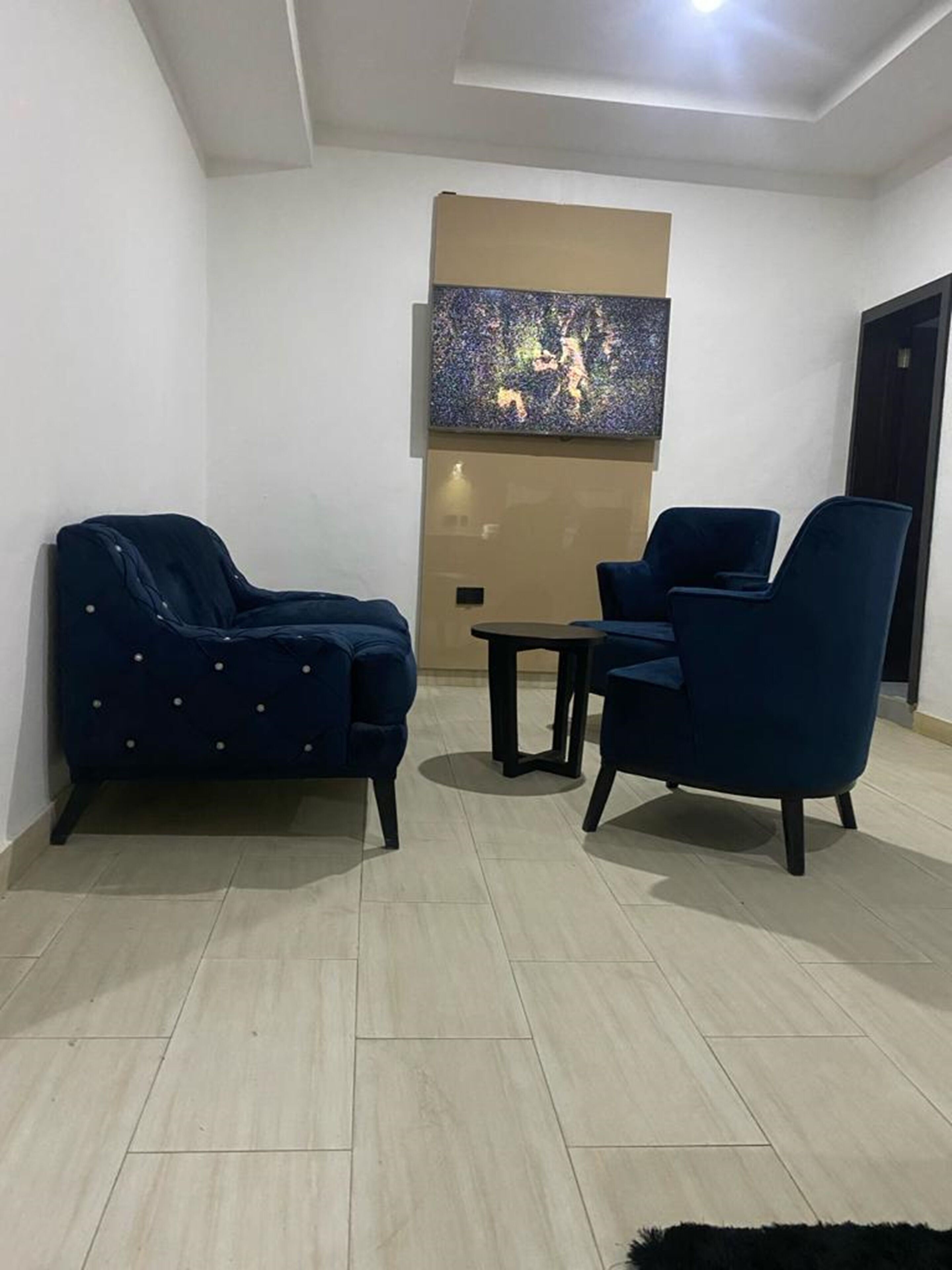 Una sala de estar moderna con dos sofás azul oscuro, una mesita redonda y un cuadro abstracto grande en la pared.