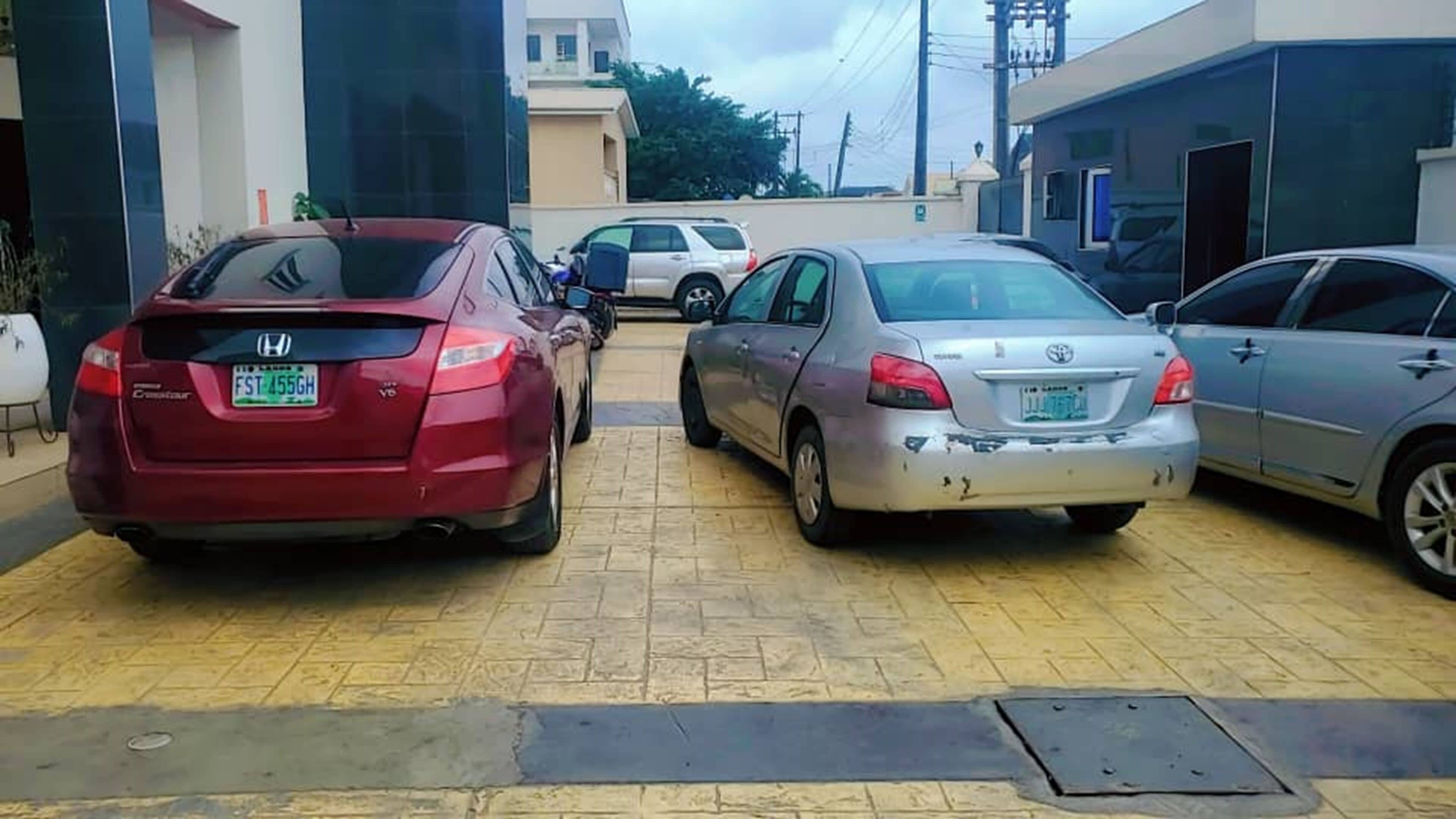 Un estacionamiento con varios automóviles, incluyendo un Honda rojo y un Toyota plateado.