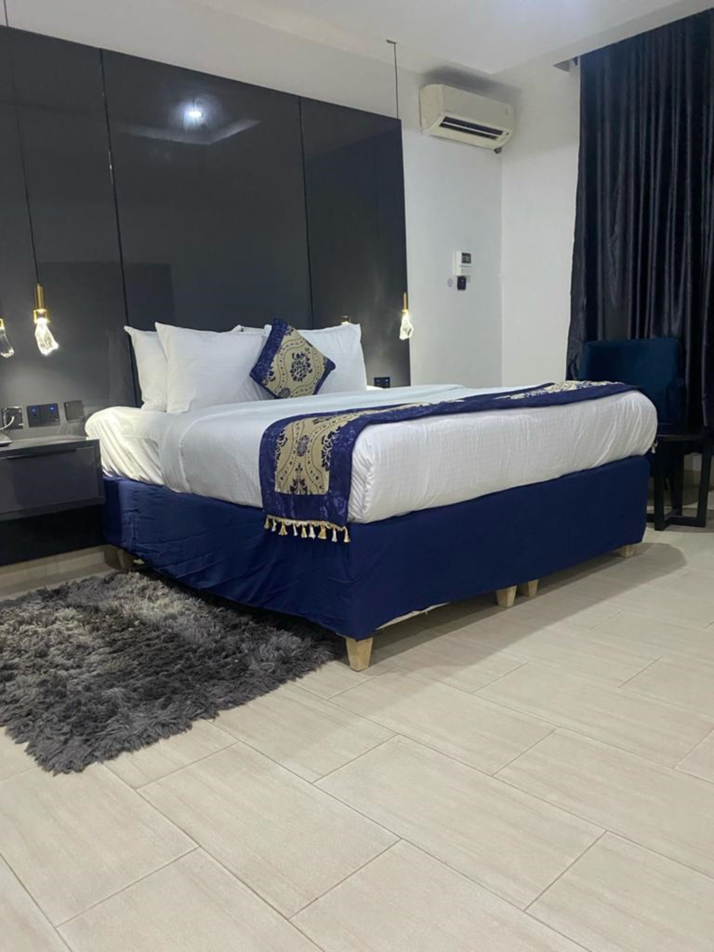 A modern bedroom with a large bed, dark wardrobe, and a small desk.