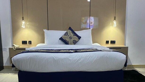 Un dormitorio moderno con una cama grande, dos mesitas de noche e iluminación colgante.