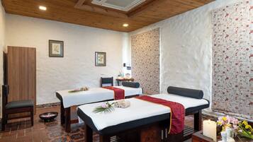 Relax in a serene spa room with two massage tables, a wooden bench, and a cozy seating area.