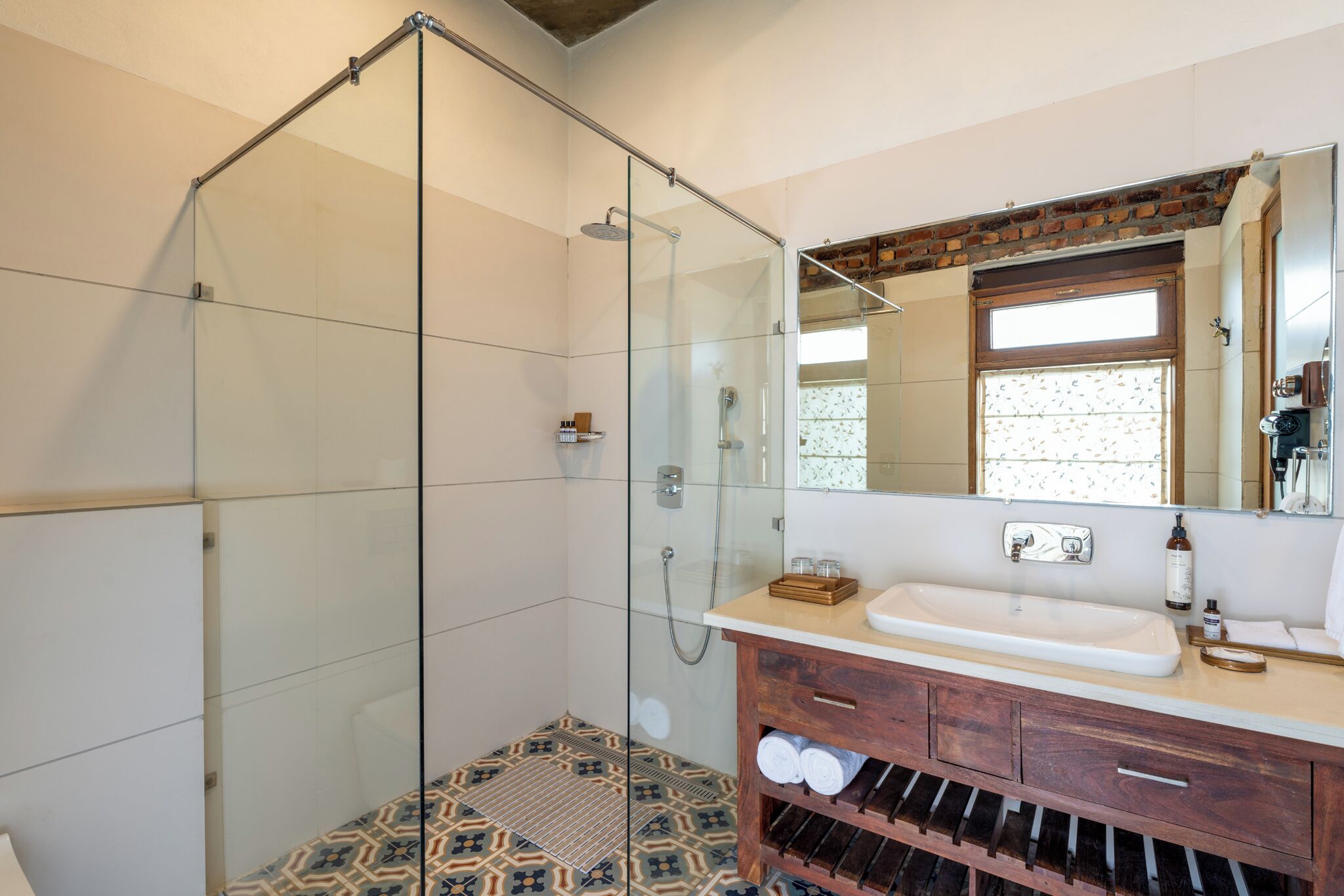 A modern bathroom with a glass-enclosed shower, a wooden vanity with a sink, and a large mirror above it.