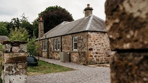 Una casa de piedra con camino de grava, una chimenea y un pequeño jardín.