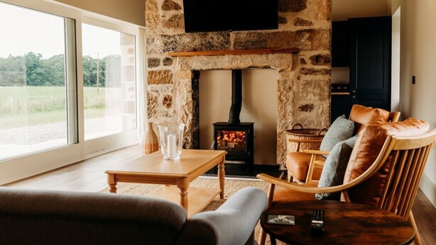 Una sala de estar acogedora con chimenea de piedra, un televisor montado encima y asientos cómodos.