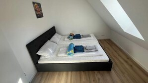 Een kleine, moderne slaapkamer met een enkel bed, dakraam en een houten vloer.