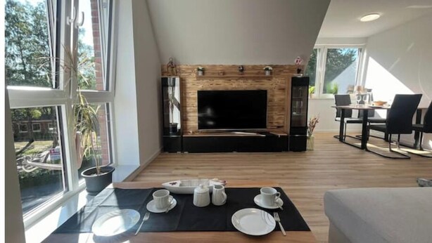 Een moderne woonkamer met een open haard, eethoek en grote ramen.