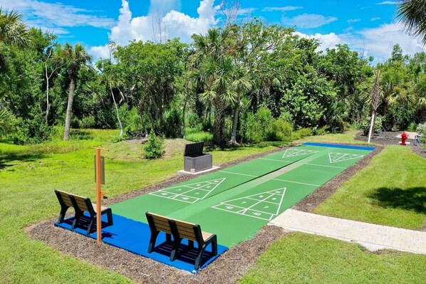A shuffleboard court with benches and a fire hydrant in a park.