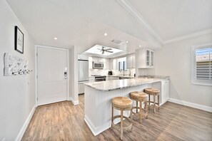 Una cocina moderna con una isla central, taburetes de bar y un ventilador de techo.