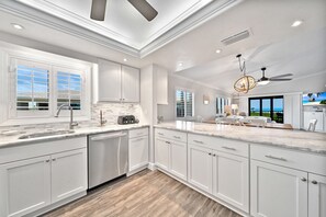 Una cocina moderna con armarios blancos, lavavajillas integrado y una isla grande con pileta.