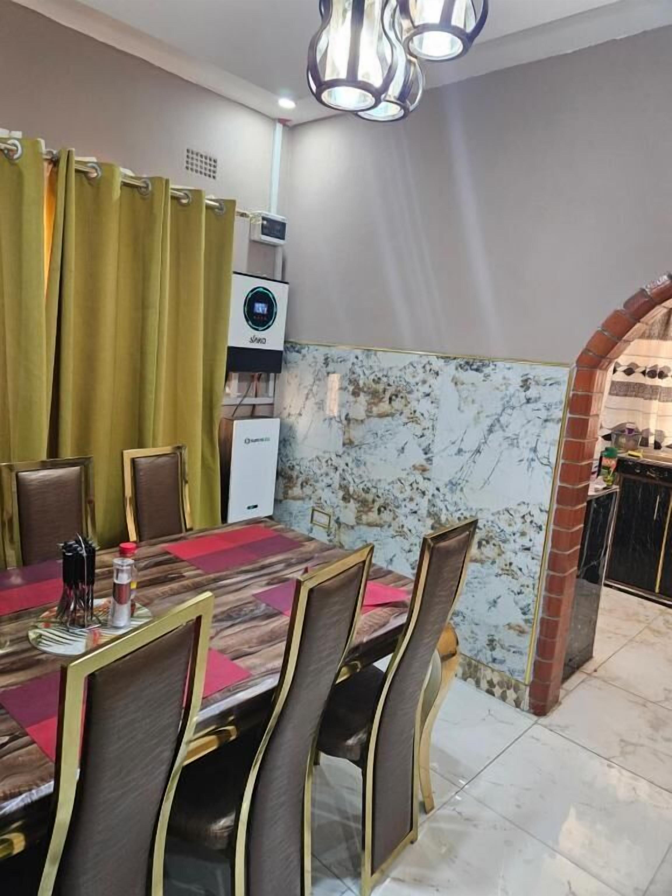 Un comedor con pared de baldosas de mármol, un arco de ladrillo y una lámpara en el techo.