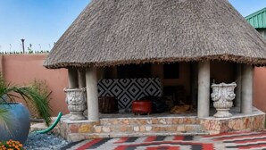 A thatched-roof structure with a patterned floor and a decorative wall. - Seven Palms Executive Lodge (Ndola)