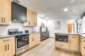 A modern kitchen with wooden cabinets, stainless steel appliances, and a tiled backsplash. - Modern Georgetown Home < 2 Mi to Blue Hole Park! (Georgetown)