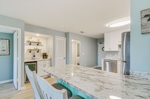 Una cocina moderna con armarios blancos, encimera de mármol y electrodomésticos de acero inoxidable.