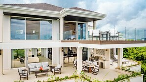 Une maison moderne à deux étages, dotée d’un balcon, de grandes fenêtres et offrant une vue sur le panorama urbain.