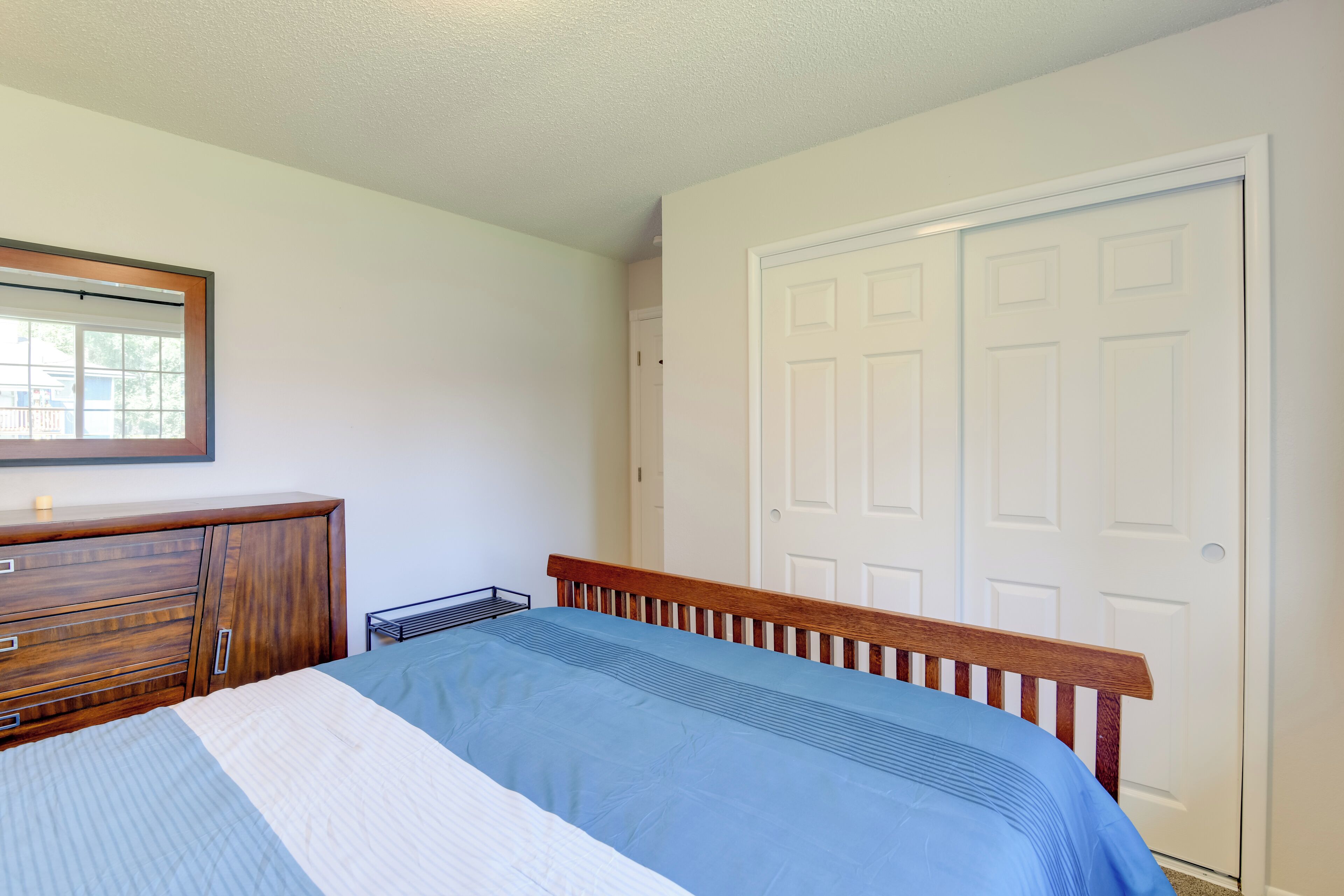 Een slaapkamer met een bed, een houten dressoir en een witte deur.