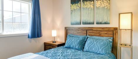 A bedroom with a bed, a nightstand, a lamp, and a window with curtains.