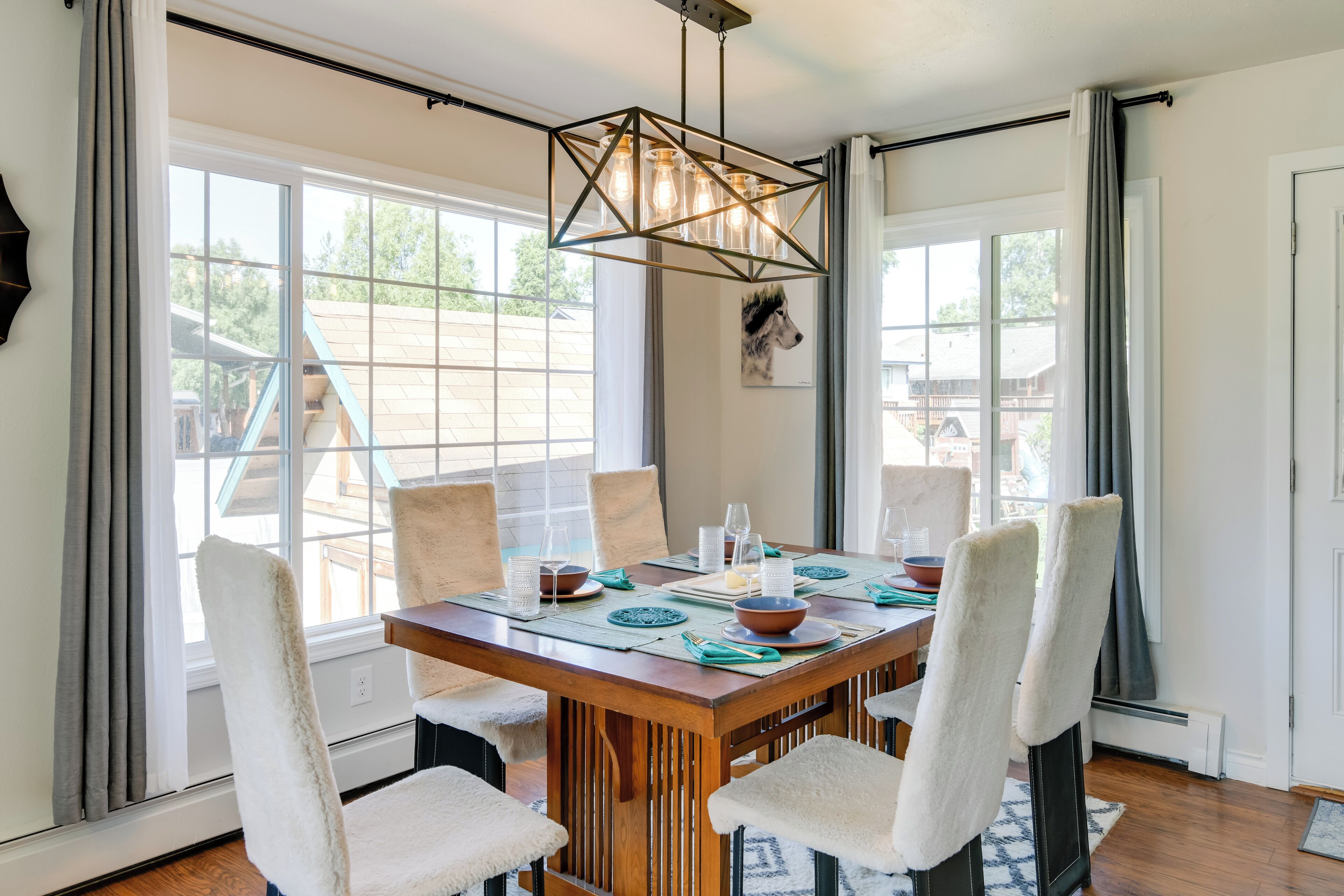 A dining area with a wooden table, white chairs, and a pendant light.