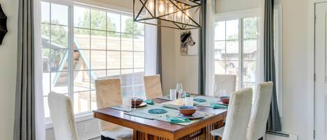 A dining area with a wooden table, white chairs, and a pendant light.