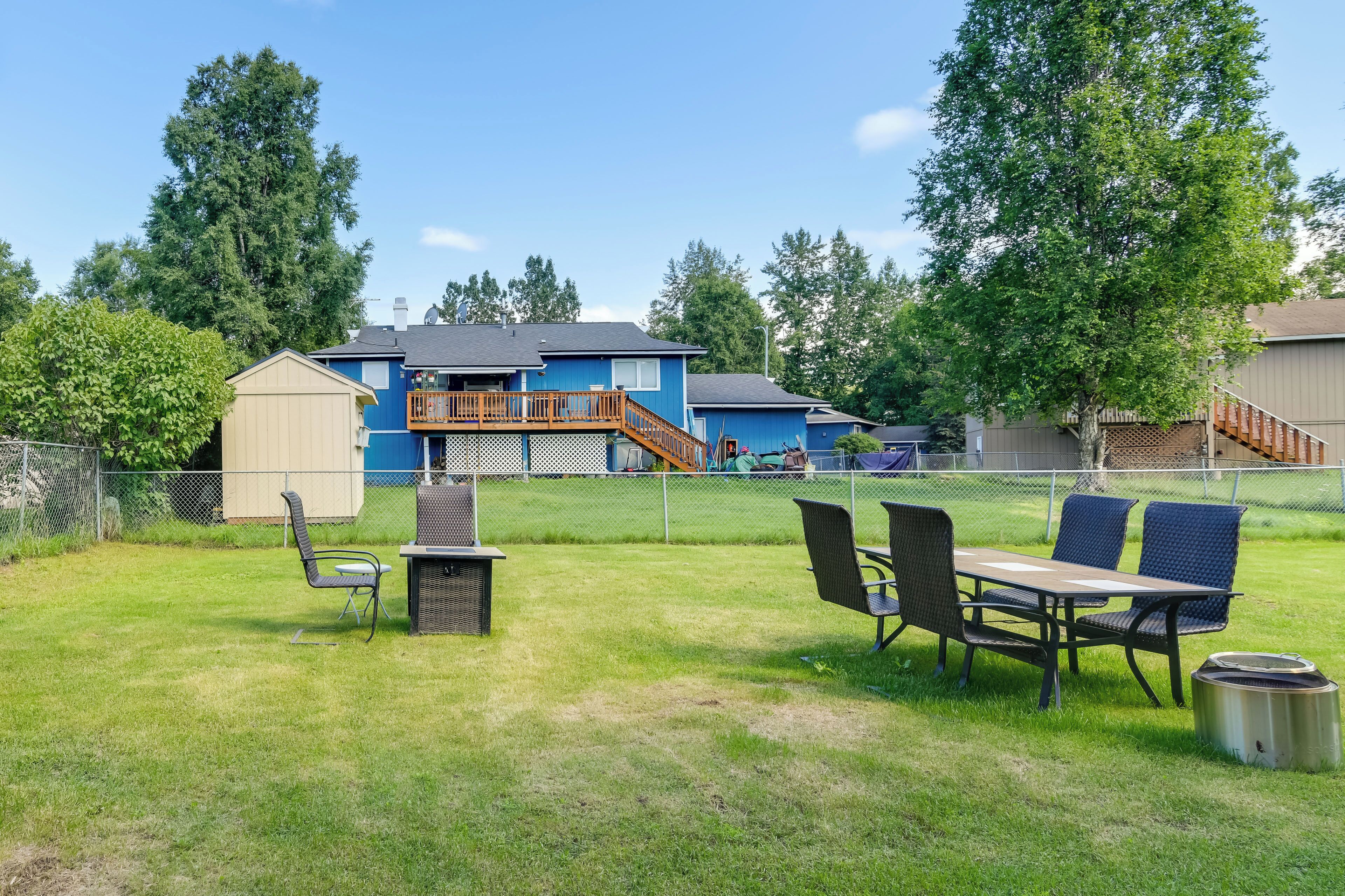 A backyard with a barbecue grill, outdoor seating, and a fenced play area.
