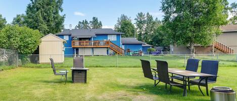 A backyard with a barbecue grill, outdoor seating, and a fenced play area.