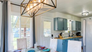 A dining area with a table set for four, a kitchen with blue cabinets, and a hanging light fixture. - Explore Chugach & Beaches! Anchorage Adventure Pad (Anchorage)