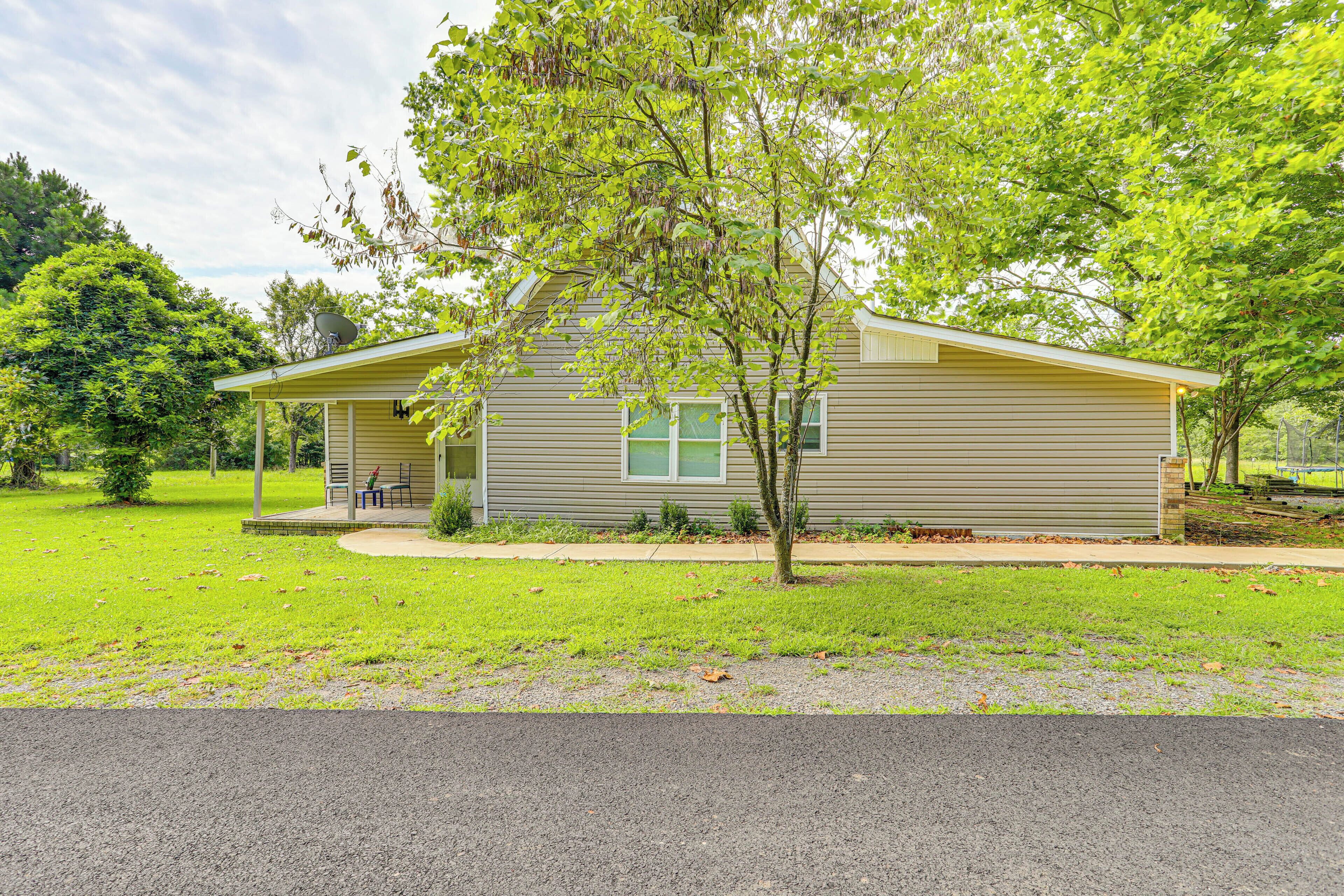 A single-story house with a covered porch, a satellite dish, and a well-maintained lawn.